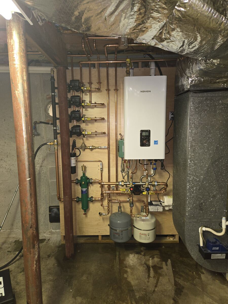 Finished wall-hung combi unit with neat copper piping, pumps and expansion tanks in a basement