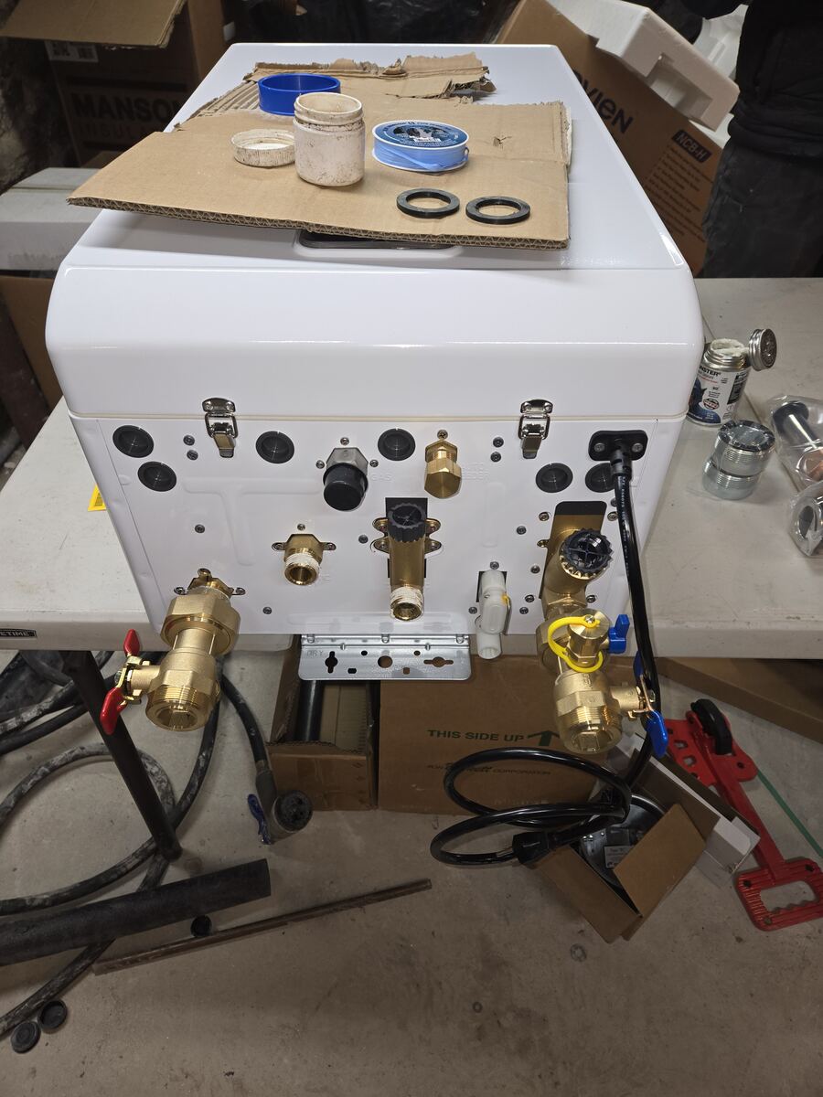 Underside of a combi unit on a work table with brass service valves attached